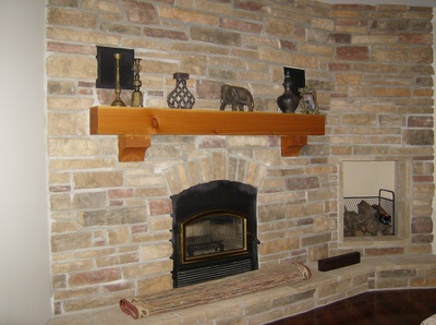 Stone wall with wood fireplace, a wood mantle and a wood elevator to the side.